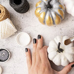 Halloween concept. Halloween DIY craft. Woman hands with a paintbrush coloring pumpkins for a holiday flat lay top view